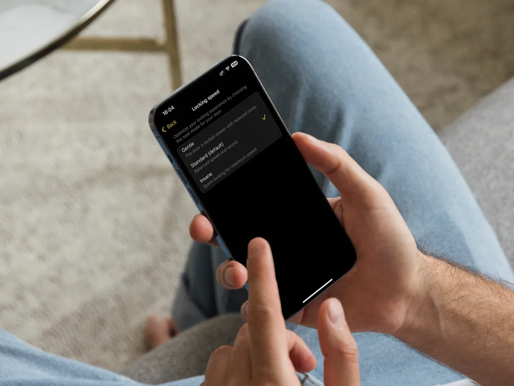 Mani che usano l'app Nuki su uno smartphone per gestire la serratura